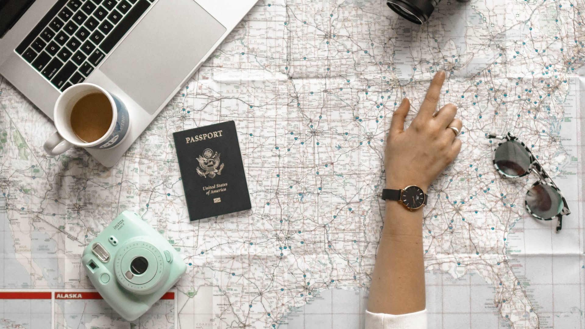 Reiseplanung mit Reiseutensilien, unter anderen Notebook, Reisepass, Kamera und Sonnenbrille